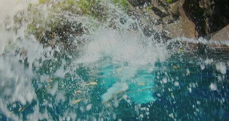 POV shot of young couple cliff jumping together in the jungle