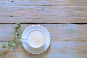 Fototapeta na wymiar A beautiful cup of cappuccino with latte art in the wooden space background. Trendy toning. Minimal composition, hipster vibes. Top view, flat lay copy space for your text.