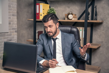 young stylish handsome businessman is reading mail in his lap top being surprised from the news he has got. a bit disappointed