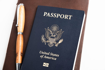 The iconic dark blue cover of an American passport with brown leather-covered journal and a...