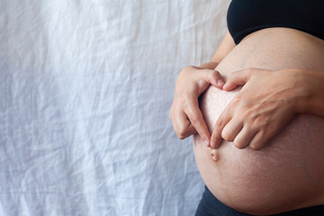 Pregnant woman at 9th Month showing heart with hands