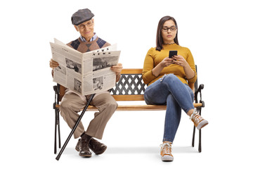 Young female with a mobile phone and a senior man reading a newspaper on a bench