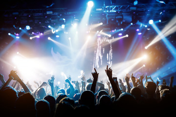 Concert hall with a lit stage and people silhouettes during a concert
