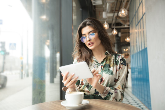 Beautiful woman using ebook reader in a cafe.
