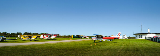 Panorama of rows of single engine planes next to a runway