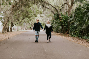 Cute Young Happy Loving Couple Walking Down an Old Abandoned Road with Mossy Oak Trees Overhanging