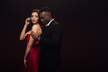 beautiful sensual interracial couple in formal wear posing isolated on black with copy space