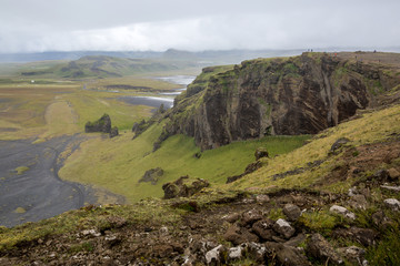 Fototapeta na wymiar High cliff above a green plain with a lake stretching to the horizon