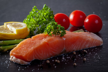 Raw trout with lemon, pepper, tomato on black stone