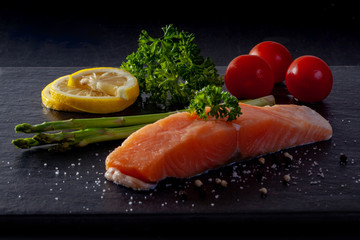 Raw trout with lemon, pepper, tomato on black stone