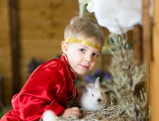 little boy plays with white Easter Bunny. on the green grass and baby bunnies, Spring Festival and birth. 