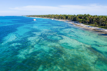 Aerial view on tropical beach with palm trees and speed boats shipping in caribbean sea
