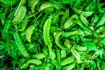 Pile of fresh green peas displayed at a farmer's market.