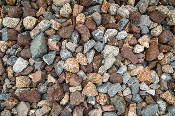 Background pattern of colorful stones and pebbles on the ground beside train track.