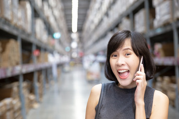 A female hand holding mobile phone in the cargo warehouse.