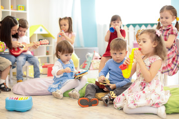 Teacher and cute kids during music lesson in preschool