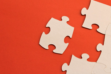 White jigsaw puzzles on red background. The concept of development of thinking. The concept of teamwork.