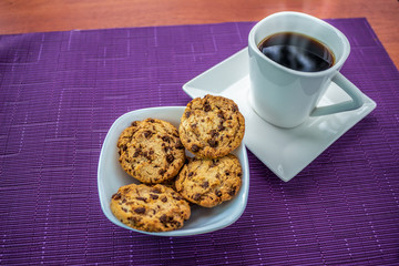 Plate of chocolate chip cookies and coffee cup