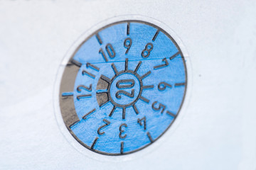 Eine blaue TÜV Plakette am Auto Kennzeichen