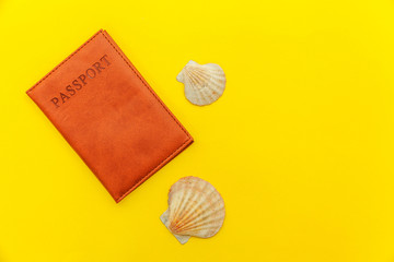 Travel vacation summer weekend sea adventure trip journey ticket tour concept. Minimal simple flat lay with passport and shell on yellow trendy modern background. Tourist essentials