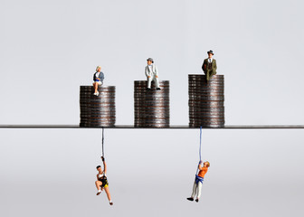 Coin piles and miniature people. A concept of economic imbalance.