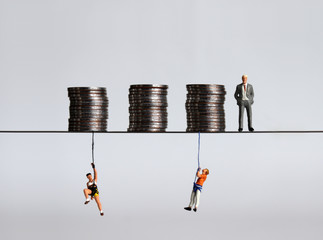 Coin piles and miniature people. A concept on the gap between the rich and the poor.