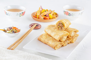 Traditional Chinese tortillas filled - bings in a plate on a white background, salads, Dam Sam snacks and cup of tea.
