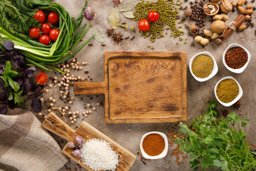 Fresh greens and tomatoes spices cereals and nuts organic healthy snacks on a textural background. Concept of healthy food. Decorative board. Frame under the text.
