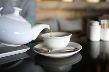 Person pours tea from white teapot