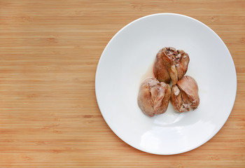 Boiled chicken liver in white plate on wooden board background.