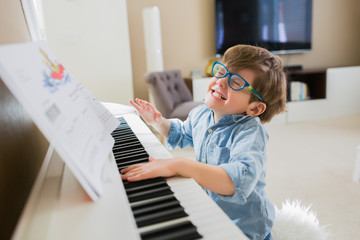 Joyful little boy playing piano