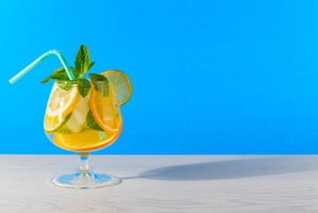 .Refreshing cocktail with orange lemon lime mint and ice on a bright blue background