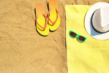 Flip flops near towel with hat and sunglasses