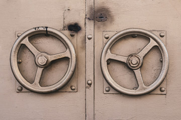 The metallic door knob in the shape of gilded steering wheel. Old door golden color with two door round handles 