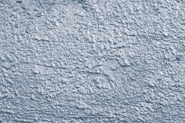 Rough concrete wall painted silver blue. Silver texture of concrete wall close-up. Silver gloss background of uneven concrete wall. Blue cement wall texture background.