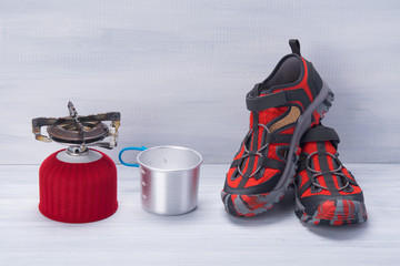 on a light grey background, Hiking shoes, cooking burner and mug