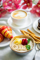 Healthy breakfast. Oatmeal with banana, strawberry and mint. breakfast with oatmeal, coffee and croissants.