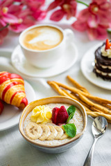 Healthy breakfast. Oatmeal with banana, strawberry and mint. breakfast with oatmeal, coffee and croissants.