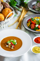 Mexican lunch, gazpacho soup with crackers and hot peppers in a white plate. tomato soup with vegetables. mexican soup. Puree soup tomato with croutons. Diet menu. tomato soup in a white plate