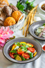 fresh salad of tomato cucumber pepper onion lemon and greens. healthy salad with fresh ripe summer...