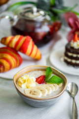 Healthy breakfast. Oatmeal with banana, strawberry and mint. breakfast with oatmeal, coffee and croissants.