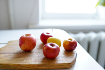 Red fresh apples on the old wooden board on light background in white kitchen. healthy food.