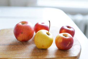 Red fresh apples on the old wooden board on light background in white kitchen. healthy food.