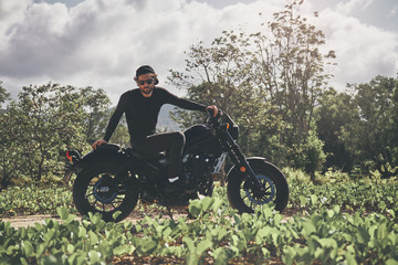 Obraz na płótnie Canvas Handsome biker man in black wear sit on classic style cafe racer motorcycle. custom made motorcycle