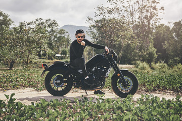 Handsome biker man in black wear sit on classic style cafe racer motorcycle. custom made motorcycle