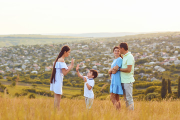 Happy family playing fun on the field at sunset.