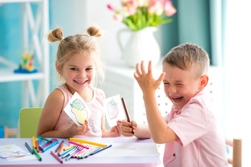 Little children play and draw with colorful pencils