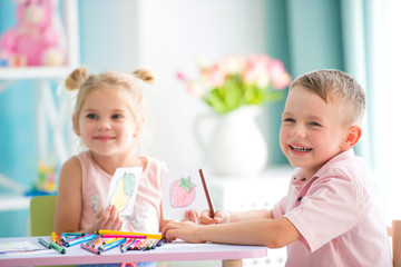 Little children play and draw with colorful pencils