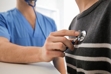 Male doctor listening heartbeat of female patient in clinic