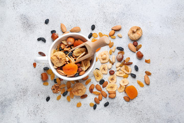 Cup and scoop with assortment of tasty dried fruits and nuts on table